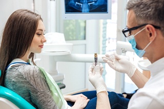 A dentist talking with a female patient about dental implants
