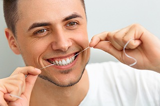 closeup of man flossing teeth 