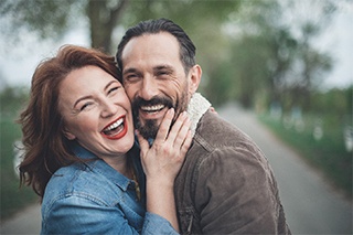 Older couple with dental implants in Fort Worth smiling outside