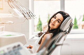 a patient smiling while sitting in the dentist’s chair