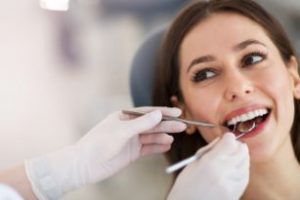 Woman with brown hair talking to a dentist about preventing dental implant infections