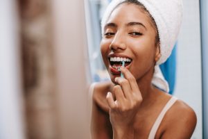 Woman looking in mirror flossing dental implants