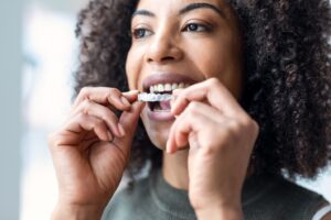 Woman about to insert clear aligner into mouth.