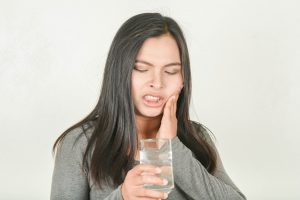 Woman with tooth sensitivity holding glass of water